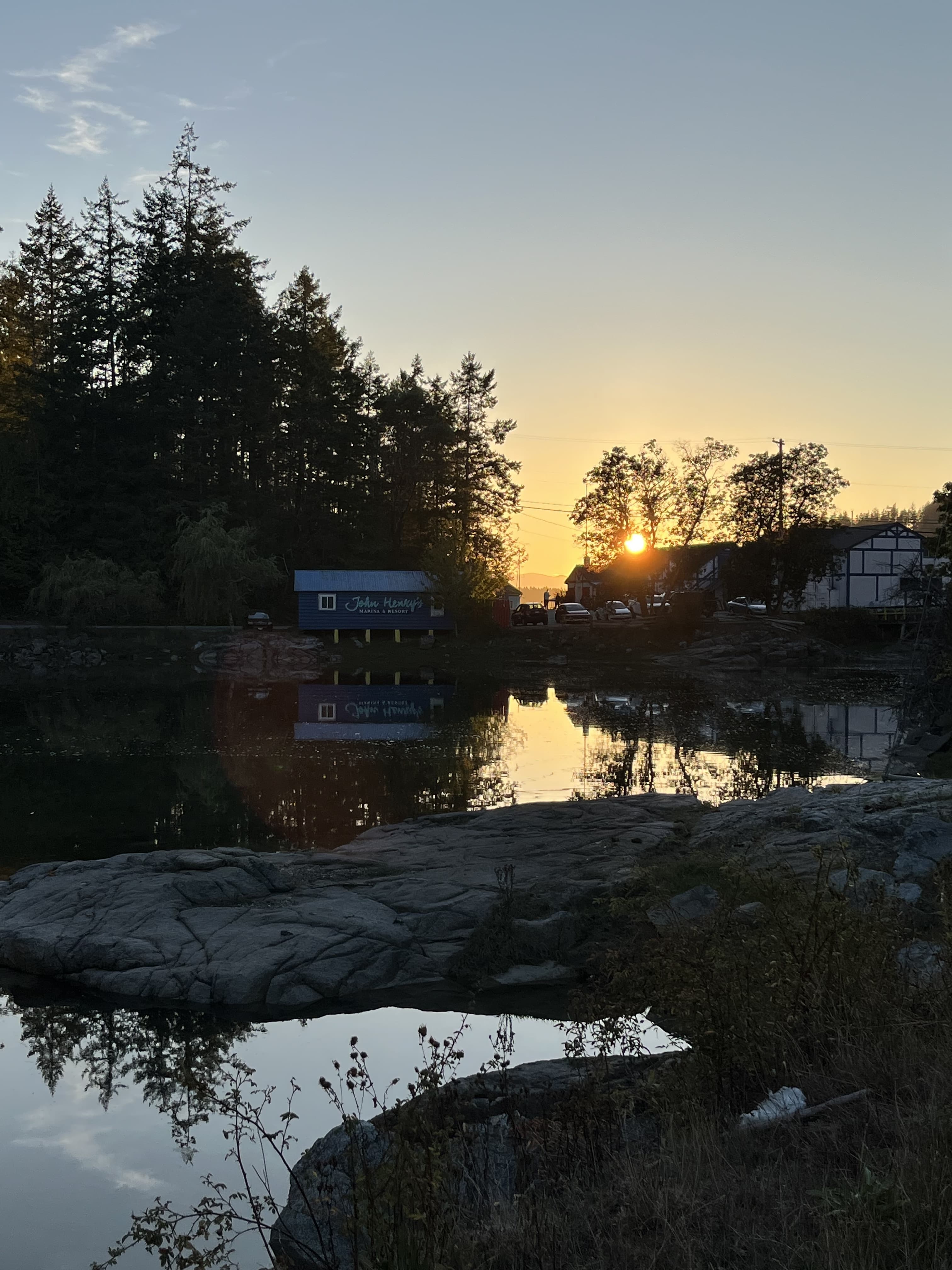 Sunset over the water at Garden Bay, BC, with rocky shoreline in the foreground